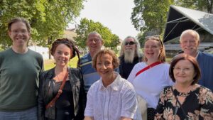 Bilde av de ansatte i administrasjonen i Seniornett, ute med sol og grønne trær i bakgrunn